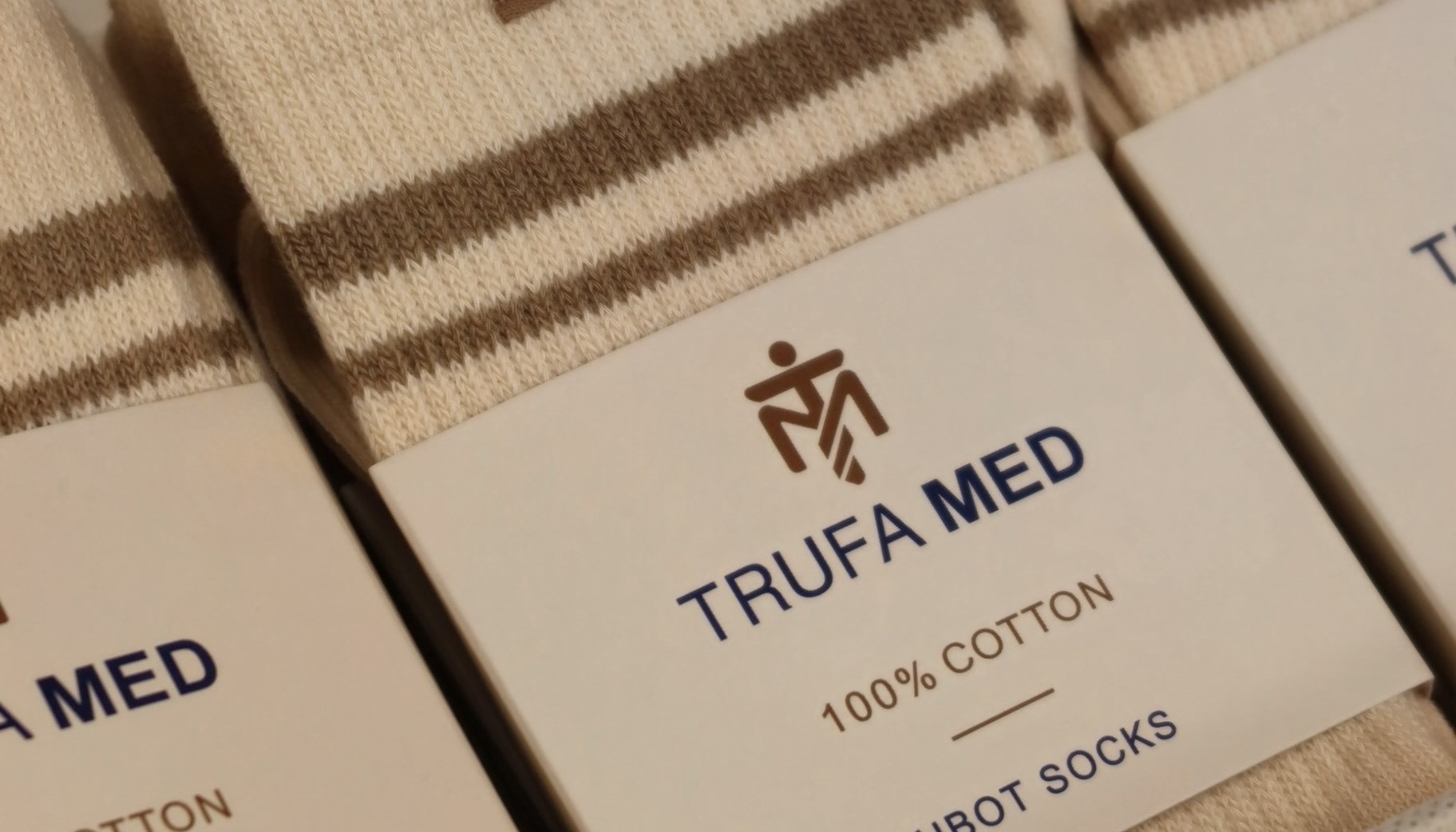 Folded cream TrufaMED HBOT socks with woven tags and retail bands reading 100% cotton