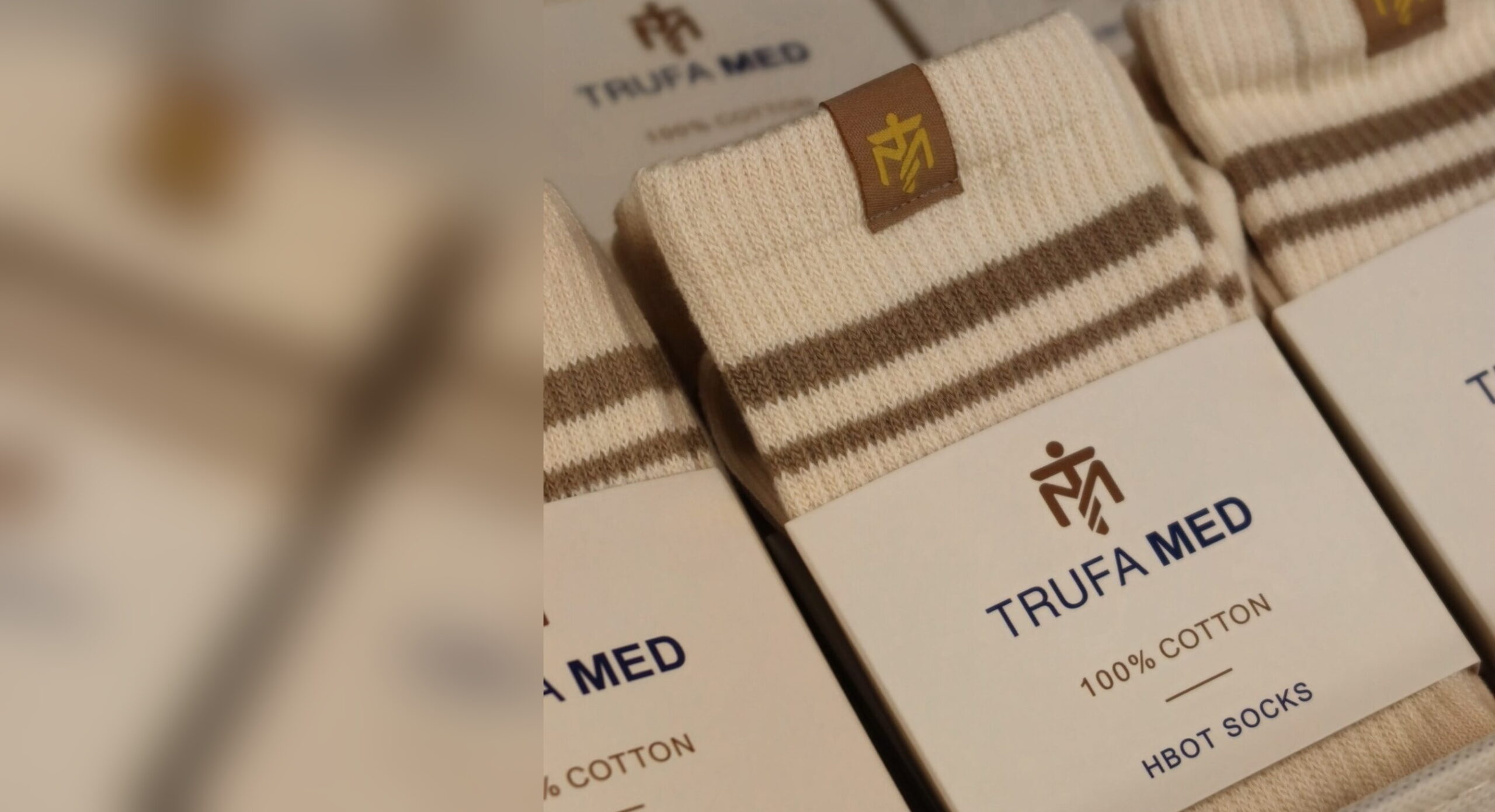 TrufaMED HBOT socks in retail packaging, gold monogram tag on the cuff and wrapper reading 100% cotton