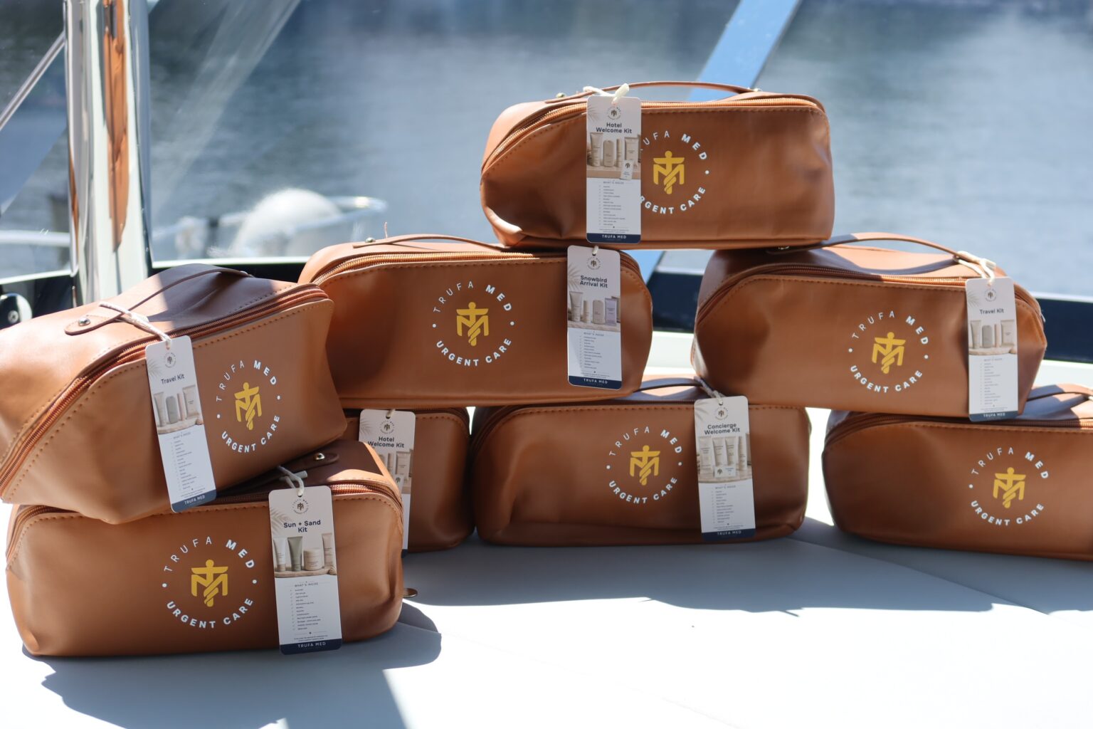 Seven tan TrufaMED medical kit bags stacked in a pyramid on a boat deck, each with a product hang tag